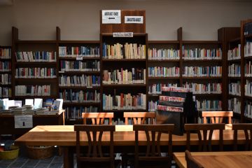 Sala principale della biblioteca con scaffali a muro e tavoli per la consultazione